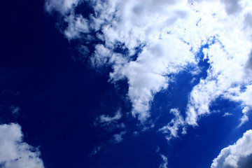 White clouds in the blue sky obscure the sun