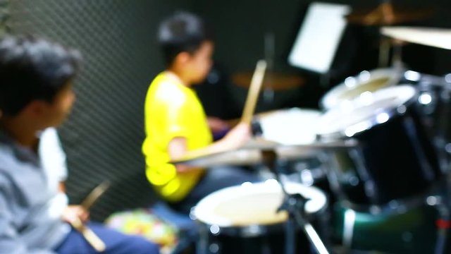 blurry vdo for background. teacher with wooden drumsticks guiding boy.
