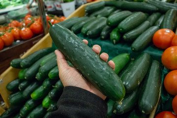 A hand holds a cucumber