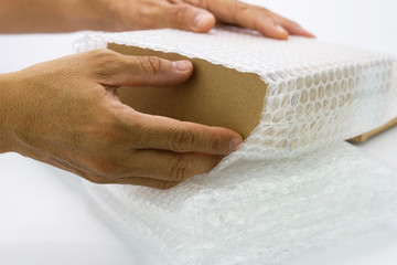 hand of man hold Bubbles covering the box by bubble wrap for protection product