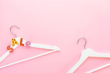 White hangers with sale text on pink background