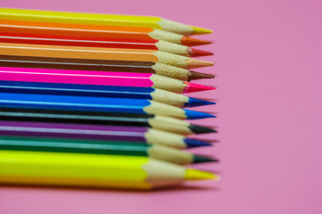 Fototapeta premium Color Pencils on a pink paper background. Selective focus