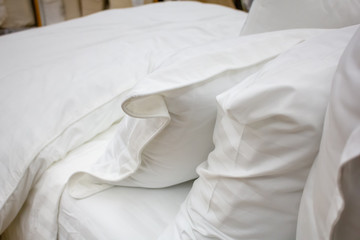 Fototapeta na wymiar A bed setting featuring white pillows, sheets and blanket