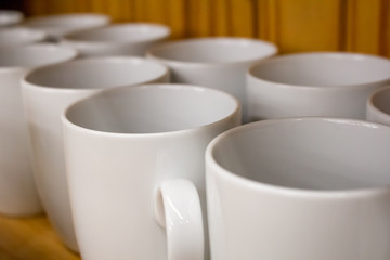 Several white ceramic mugs on a shelf
