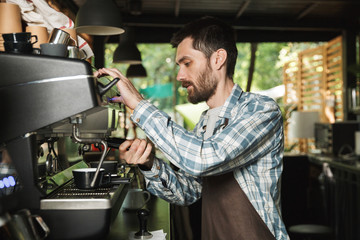 Fototapeta na wymiar Image of young barista man making coffee while working in cafe or coffeehouse outdoor