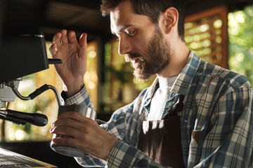 Image of caucasian barista boy making coffee while working in cafe or coffeehouse outdoor