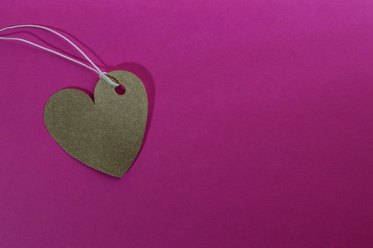 gold heart paper tag on pink background