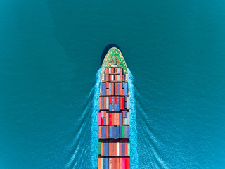 Aerial top view container ship full speed with beautiful wave pattern on the blue sea for...