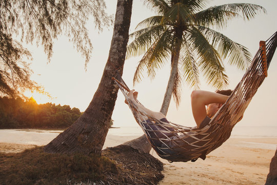 tourist relaxing in hammock on tropical beach with coconut palm trees, relaxation and leisure tourism