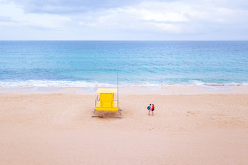 small couple in minimalist beach landscape near yellow hut and blue ocean, summer holiday travel to Canary islands