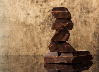 Blocks and pieces dark chocolate on a stone background and copy space for text