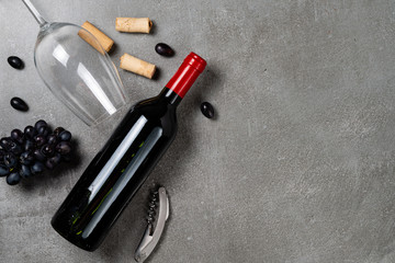 Bottle of wine, glass, opener, corks and grapes on concrete background. Copy Space.