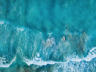 aerial top down view of surfer with surf board in ocean wave from drone
