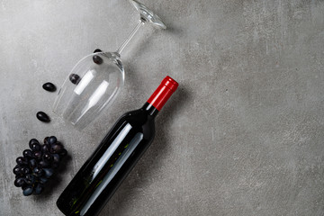Bottle of wine, glass and grapes on concrete background. Copy Space.