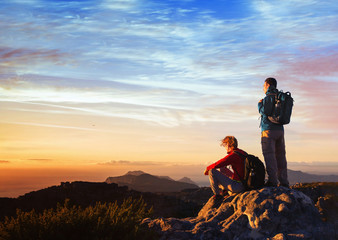 adventure travel, couple of hikers relaxing on top of mountain, active tourism with backpack