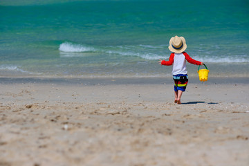 Two year old toddler boy playing with beach toys on beach