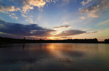 Fototapeta na wymiar Sunset on the forest lake beautiful clouds.