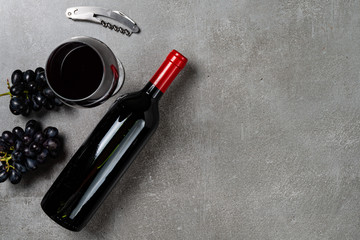 Wine bottle, glass, opener and grapes on concrete background. Copy Space.