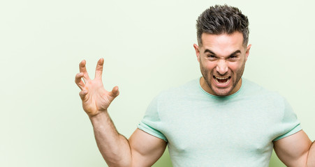 Naklejka premium Young handsome man against a green background screaming with rage.