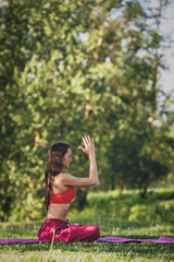 Young woman practicing yoga outdoors. Female meditate outdoor in the summer city park.