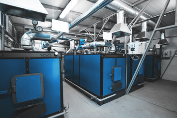 water-heating solid fuel boilers installed in a row in boiler room. Blue toning