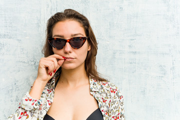 Young european woman wearing bikini with fingers on lips keeping a secret.