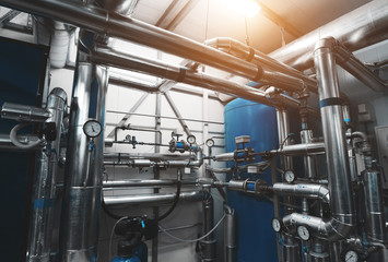 Fototapeta premium Boiler room. Water treatment pipes and pressure gauges installed for pressure control. Expansion Tank. Ventilation System. Blue toning with sunflare