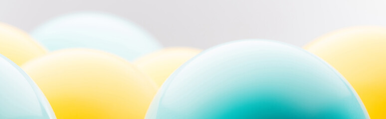 Panoramic shot of blue and yellow balloons isolated on grey