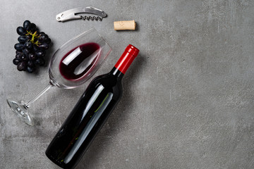 Glass with wine, bottle, opener and grapes on background of congreto. Copy Space.