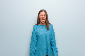 Young pretty woman wearing a blue sweater doubting and shrugging shoulders