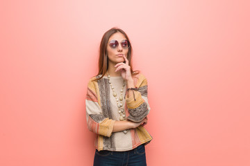 Young hippie woman on pink background doubting and confused