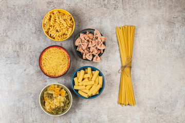 Fideos variedad de pastas secas vista desde arriba sobre fondo gris aislado