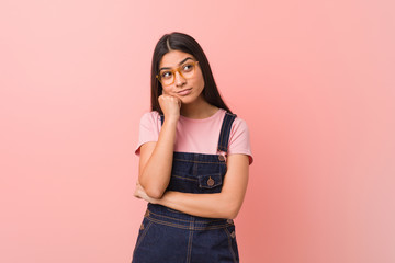 Young pretty arab woman wearing a jeans dungaree who feels sad and pensive, looking at copy space.