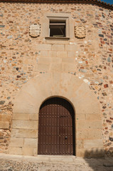 Wooden door in old building facade with rounded top at Caceres