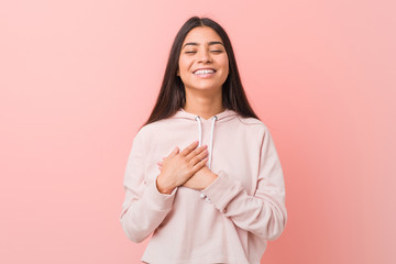 Young pretty arab woman wearing a casual sport look laughing keeping hands on heart, concept of happiness.