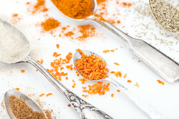 close up view of colorful spices in shiny spoons on white background