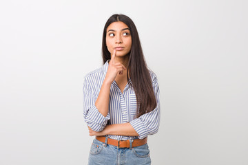 Young pretty arab woman looking sideways with doubtful and skeptical expression.