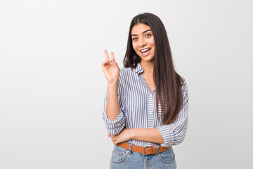Young pretty arab woman joyful and carefree showing a peace symbol with fingers.