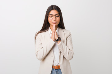 Young business arab woman isolated against a white background holding hands in pray near mouth, feels confident.