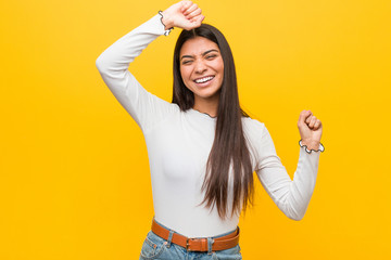 Young pretty arab woman against a yellow background celebrating a special day, jumps and raise arms with energy.