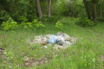 Landscape view on a green forest and grass with huge garbage dump. Nature pollution concept