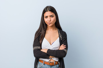 Young natural and pretty arab woman frowning face in displeasure, keeps arms folded.