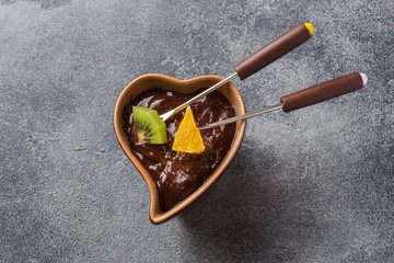 Chocolate fondue with fruit on a dark concrete background. concept summer party. Copy space