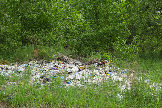 Landscape view on a green forest and grass with huge garbage dump. Nature pollution concept