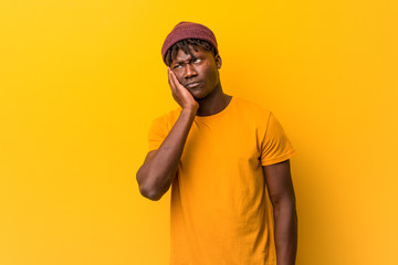 Young black man wearing rastas over yellow background who is bored, fatigued and need a relax day.