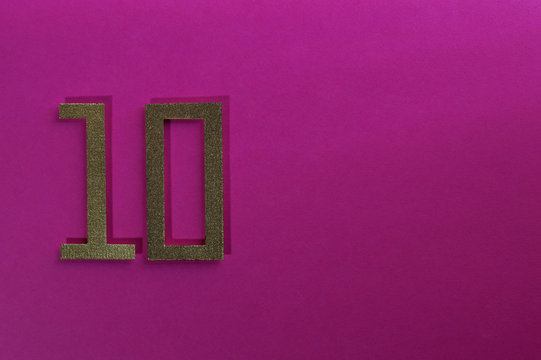 gold number ten on pink background