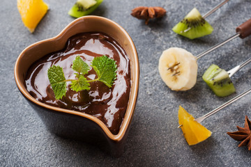 Chocolate fondue with fruit on a dark concrete background. concept summer party. Copy space