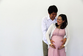Close-up pregnant woman with husband happy smile portrait and hug on white background.