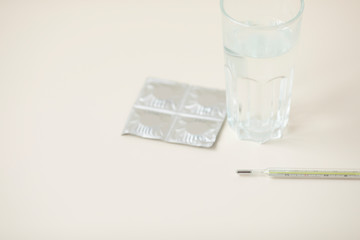 medical glass thermometer on the background of various drugs, vitamins , antibiotics and pills are with stethoscope and blank prescription