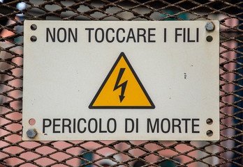 Close-up of a danger sign in a train station, warning not to touch high voltage wires: 